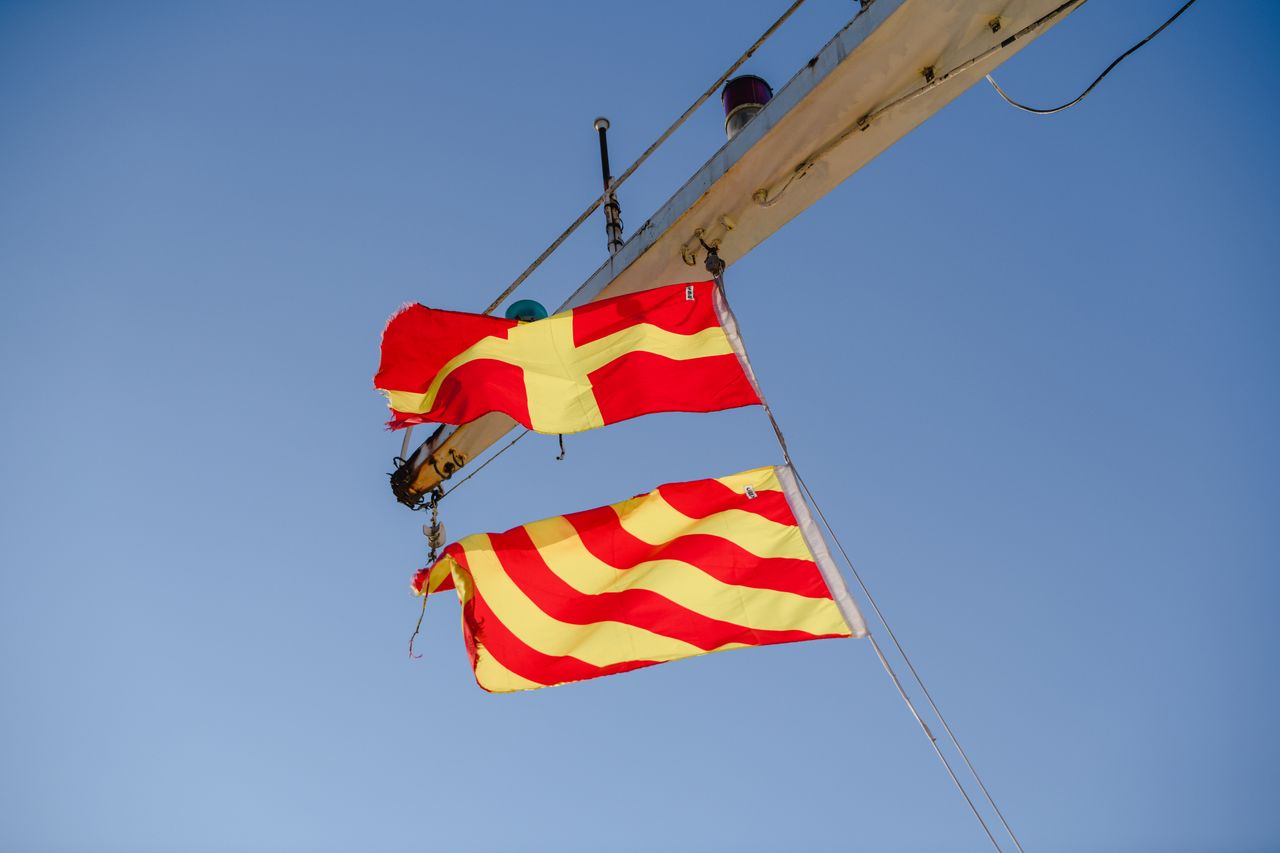 A red signal flag snapping against an overcast sky