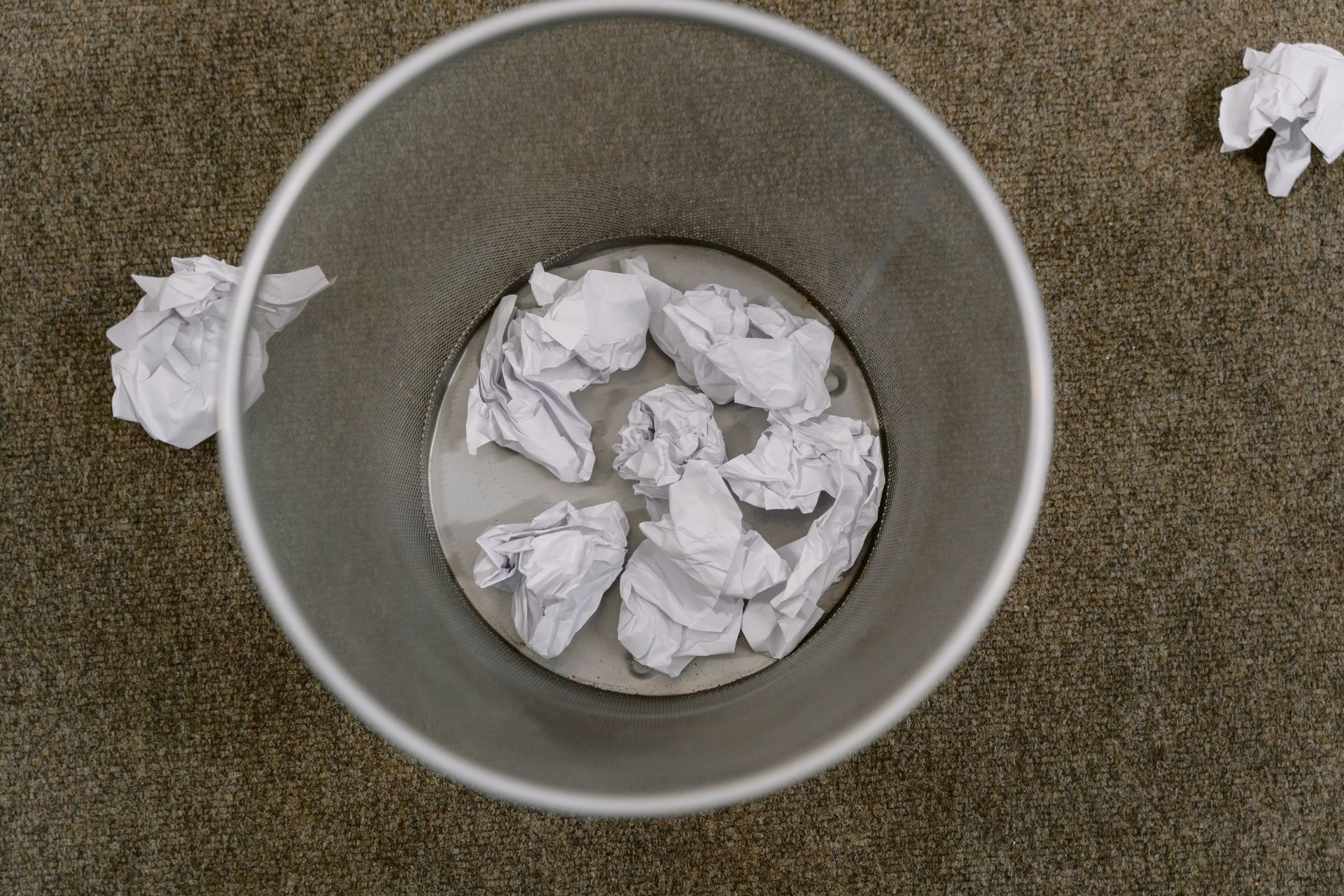 A bin of crumpled paper beside a desk