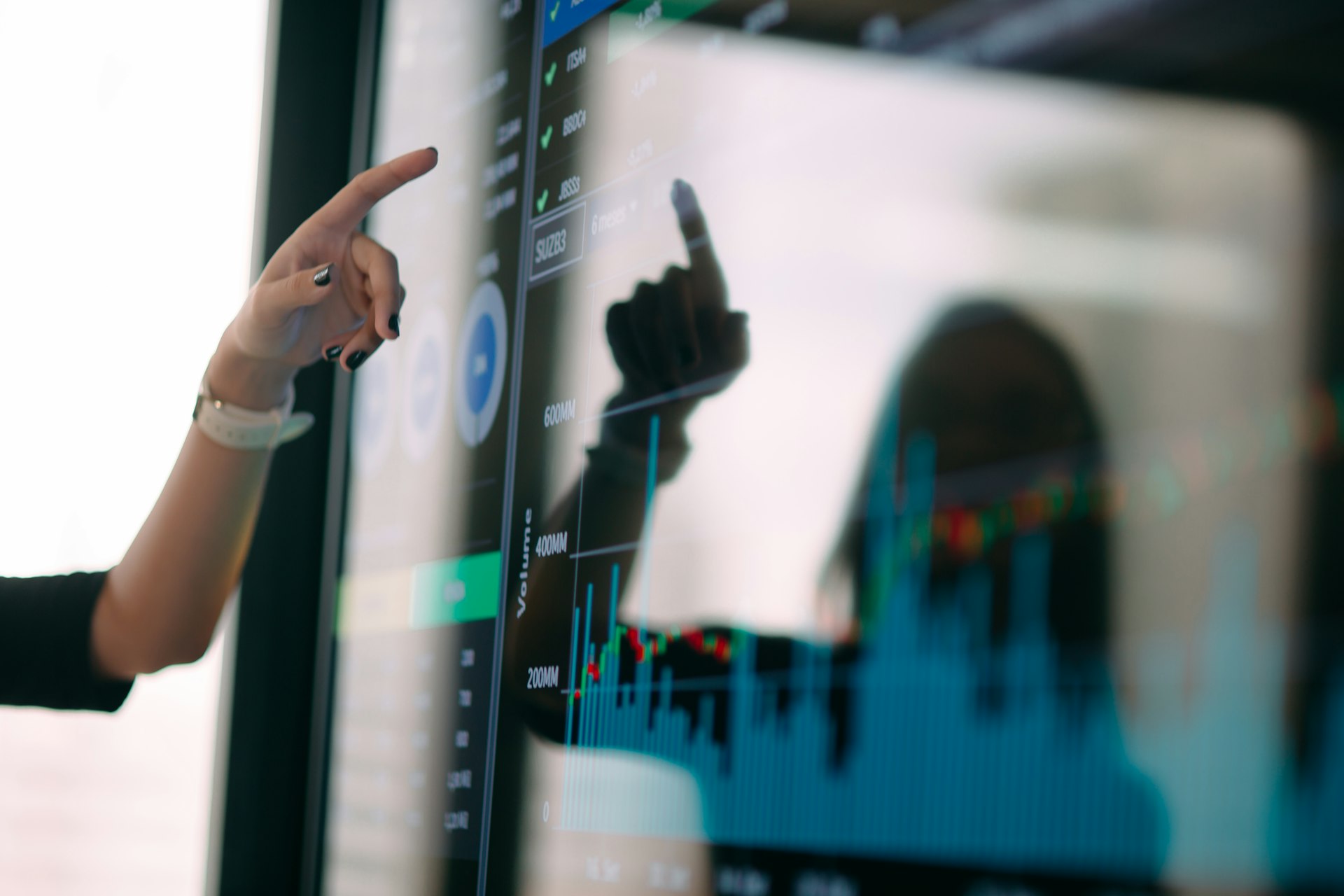 An analyst pointing at a chart of site metrics on a monitor