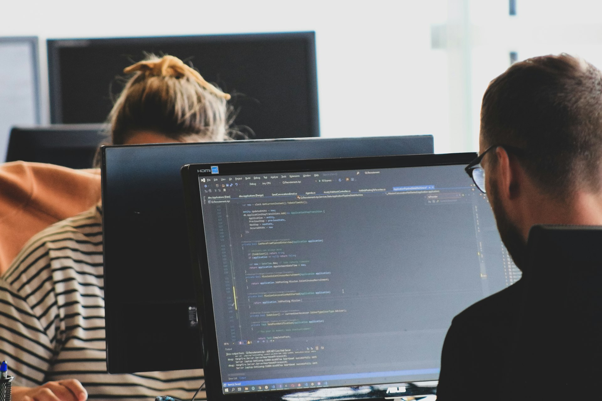 A developer reviewing code across two monitors