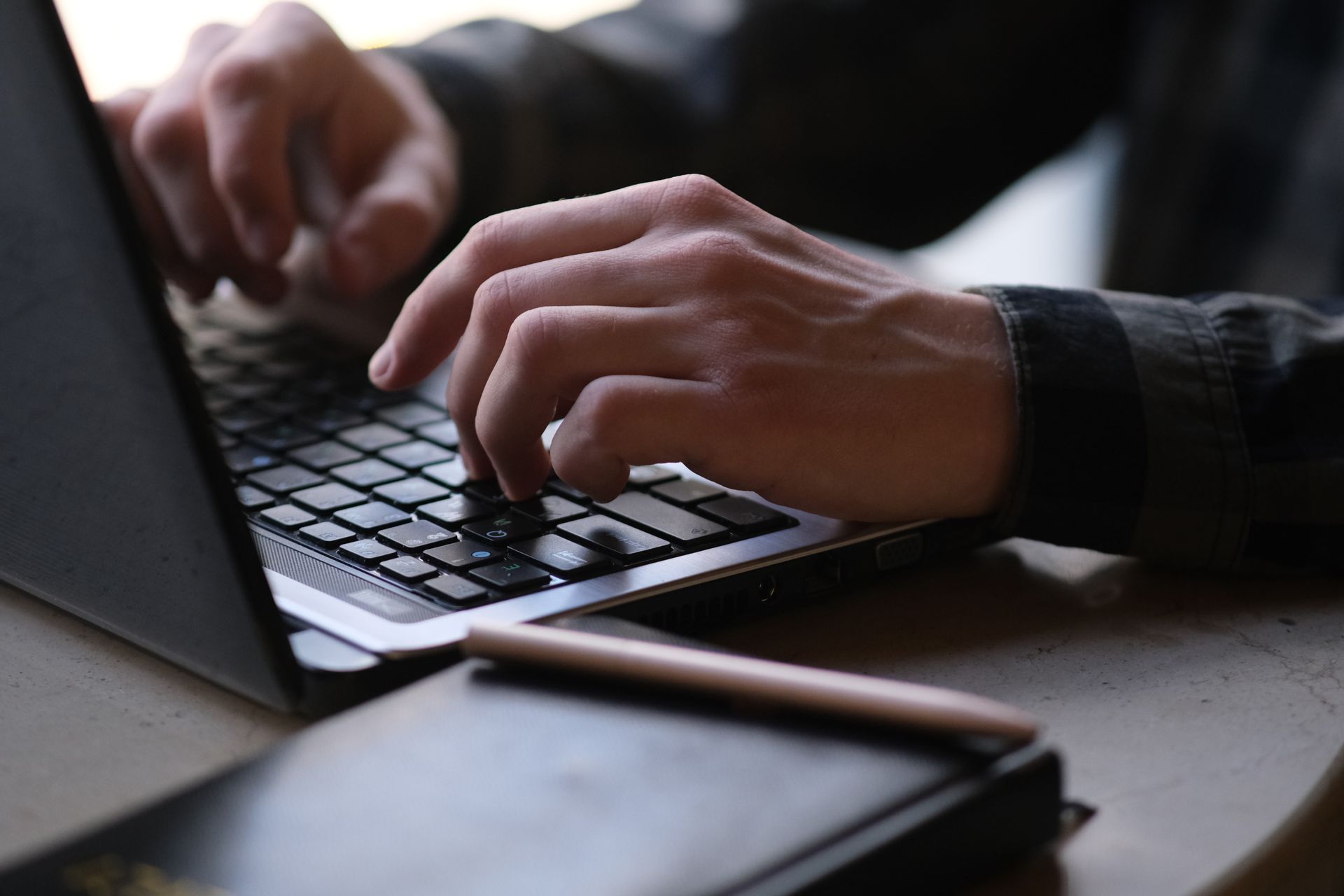 An article being written on a laptop beside handwritten notes