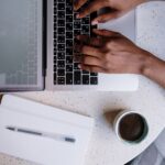 A person blogging on a laptop in a cafe
