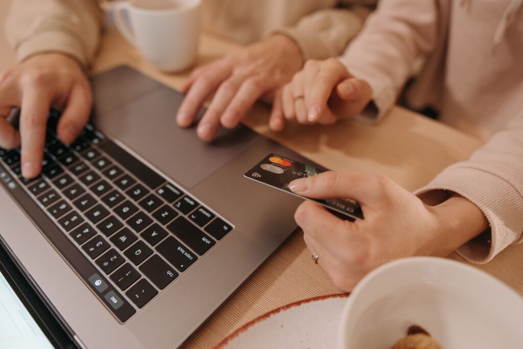 Hands typing on a laptop with a shopping cart