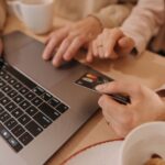 Hands typing on a laptop with a shopping cart