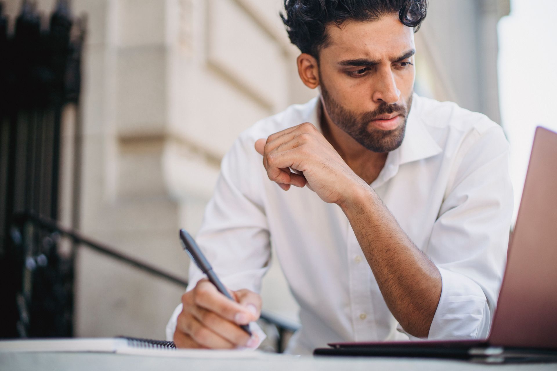 A person taking notes at a laptop