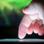 A finger tapping a button on a smartphone