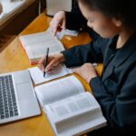 A student studying with a laptop and notes