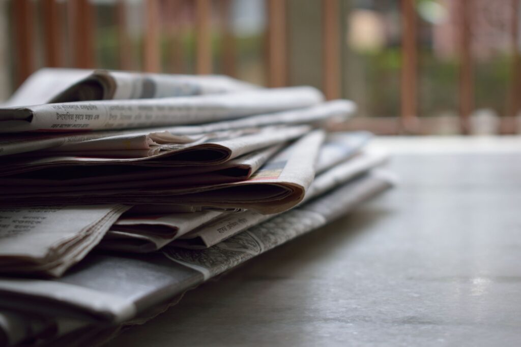 A tall stack of printed articles on a desk