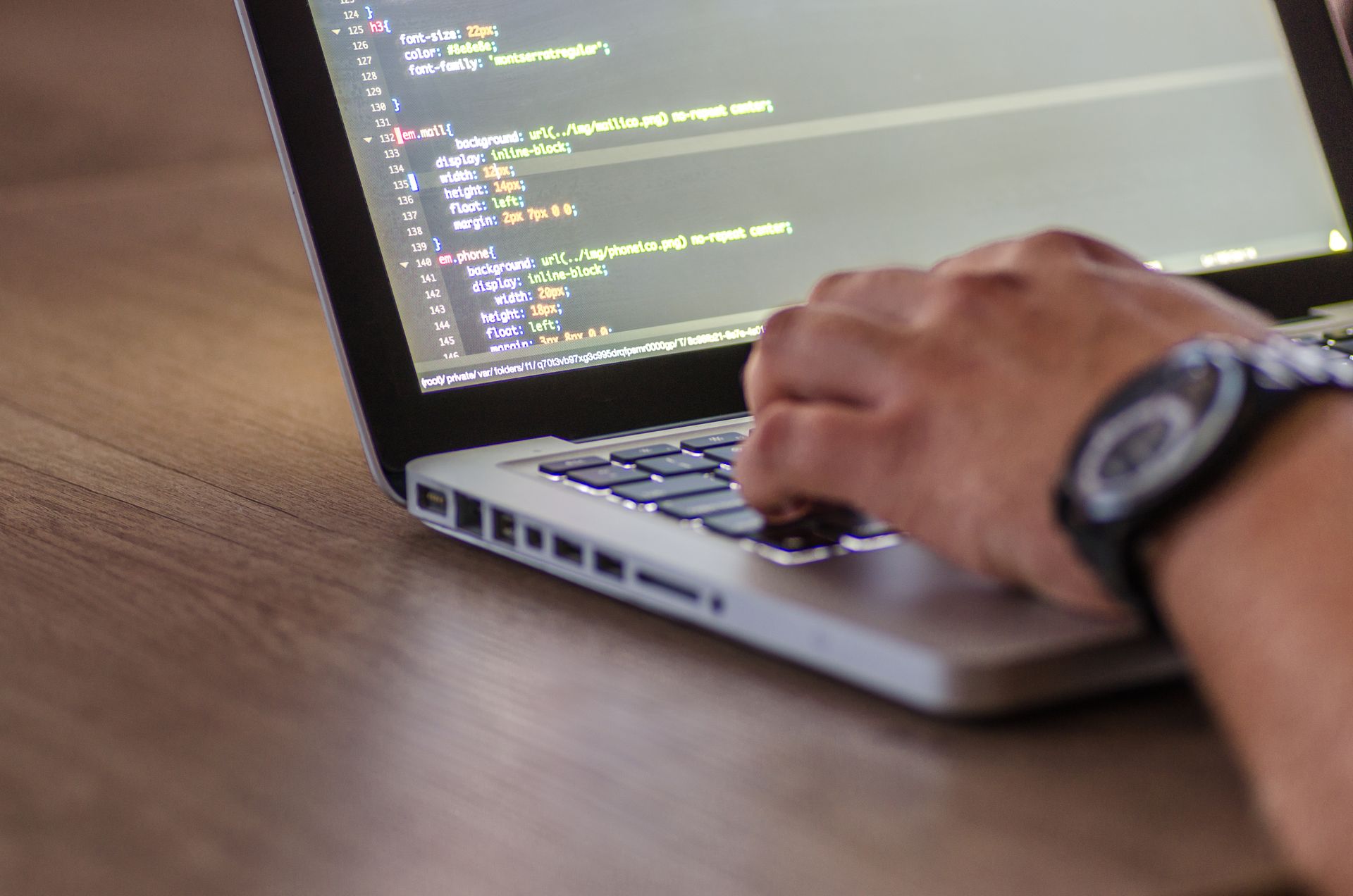 A web developer typing code on a laptop